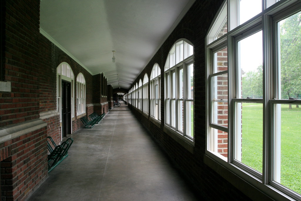 a long empty hallway. There are doors on one side and windows on the other.